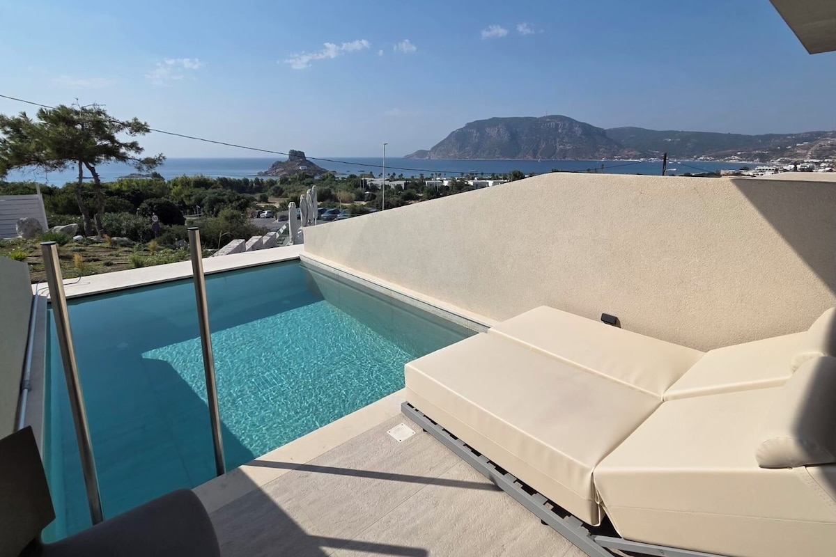 A pool area with a view of the sea and a mountain.