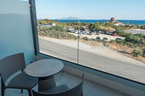 A balcony with a view of a coastal road, parked cars, and a distant rocky outcrop. - Kefalos View (Kos)