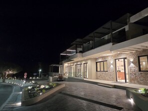 A modern building with a glass facade, a stone accent wall, and a landscaped entrance area. - Kefalos View (Kos)