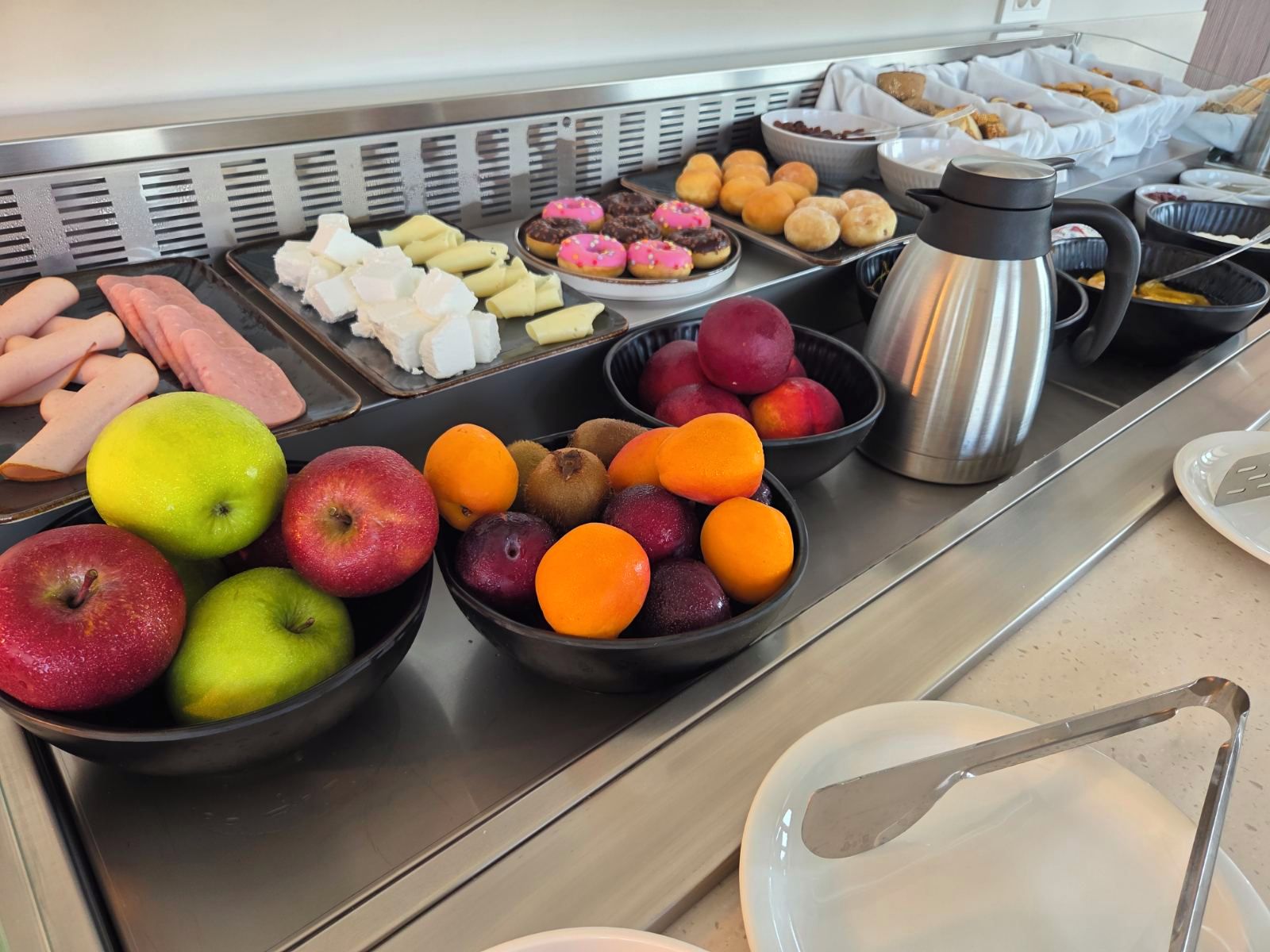Ein reichhaltiges Buffet mit verschiedenen Früchten, Gebäck und einer Kaffeekanne.