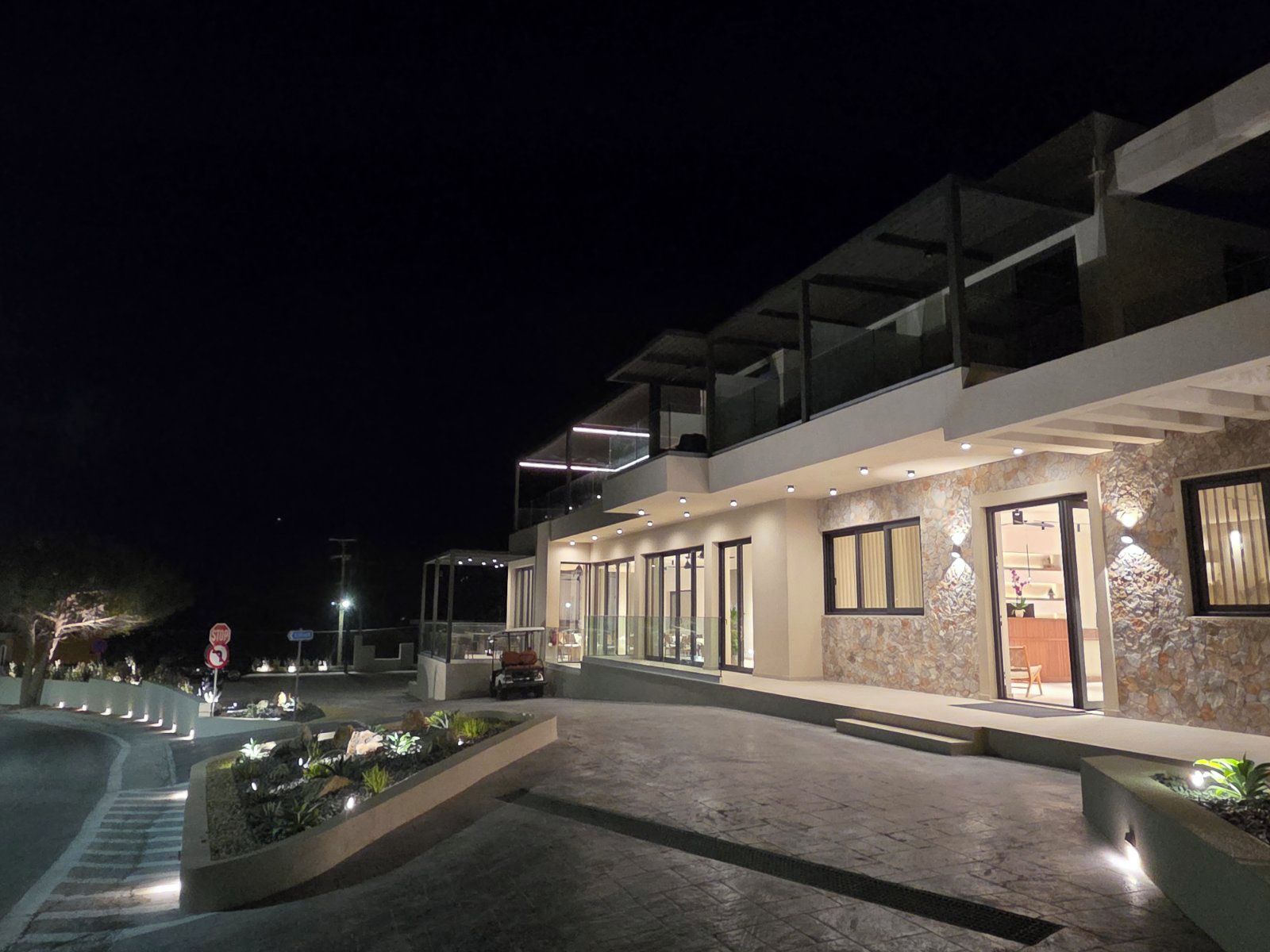 A modern building with a glass facade, a stone accent wall, and a landscaped entrance area.