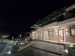 Un edificio moderno con fachada de vidrio, un muro de acento de piedra y un área de entrada ajardinada.