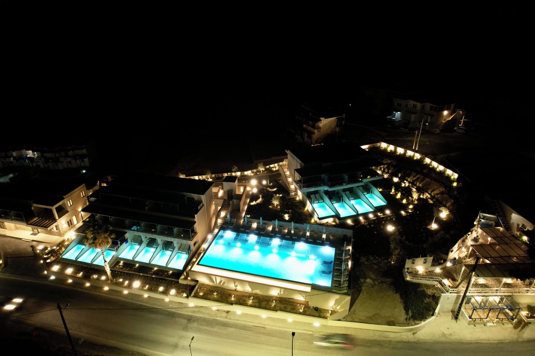 A modern building with multiple swimming pools and outdoor lighting.
