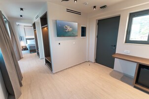 Un pasillo de hotel con una cama, un televisor, una puerta y una ventana.