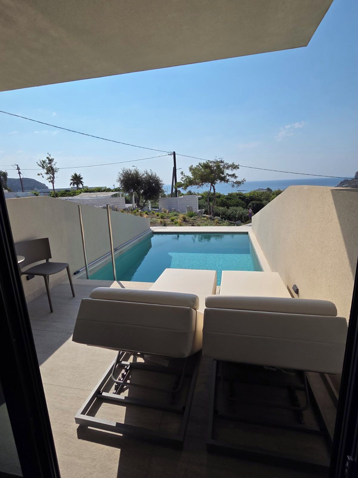 Ein Poolbereich mit zwei Liegestühlen und Meerblick.