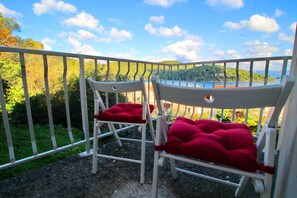 Two white chairs with red cushions on a balcony with a metal railing, overlooking a body of water and greenery. - Apartments Nodilo - One Bedroom Apartment With Balcony and Sea View (Mljet)