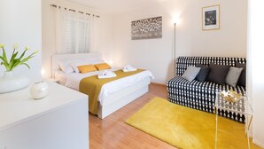 A hotel room with a bed, a sofa, a desk, and a floor lamp. - Apartments Lotea - Two-bedroom Apartment With Terrace and Sea View (Konavle)
