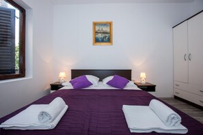 Ein Schlafzimmer mit einem Bett, zwei Nachttischen, einem Gemälde und einem Kleiderschrank.