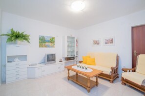A living room with a sofa, a coffee table, a television, a bookshelf, and a door. - Apartments Paco - Superior Two-bedroom Apartment With Terrace and Sea View A1 (Postira)