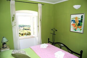 A bedroom with a bed, a window with curtains, a bedside lamp, a wall-mounted light, and a painting. - Villa Tony - Five Bedroom Villa With Terrace, Swimming Pool and Sea View (Dubrovnik)