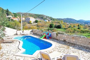 A swimming pool with a stone deck, lounge chairs, and a slide. - Villa Tony - Five Bedroom Villa With Terrace, Swimming Pool and Sea View (Dubrovnik)