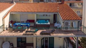 A residential building with a tiled roof, outdoor seating area, and a balcony with railings. - Apartments Ribarevic - Studio With Balcony (Makarska)