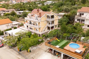 Ein mehrstöckiges Wohngebäude mit Balkon, Schwimmbad und umzäunter Garten.