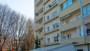 Um edifício residencial com vários andares, varandas, aparelhos de ar condicionado e telhado plano.