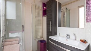 Uma casa de banho moderna com cabine de duche em vidro, toucador com espelho grande e sanita com função bidé.
