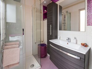 Ein modernes Badezimmer mit Duschkabine aus Glas, einem Waschtisch mit großem Spiegel und einer Toilette mit Duschwannenaufsatz.