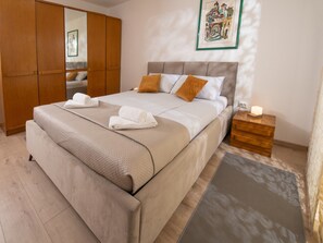 Ein Schlafzimmer mit einem Bett, einem Holzschrank, einem Nachttisch mit Lampe und einem gerahmten Bild an der Wand.