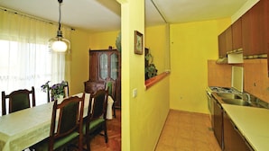 Una cucina compatta con piano cottura a gas e lavello, una zona pranzo con tavolo e sedie, e un lampadario.