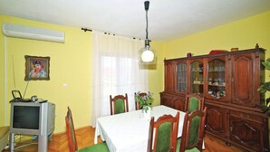 Zona pranzo con tavolo, sedie, televisore e un armadio.