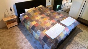 A neatly made bed with a colorful quilt, a bedside table with a lamp, and a framed picture on the wall. - Holiday Home Saniv - Holiday Home (Draz)