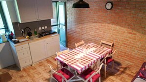 A dining area with a checkered tablecloth, wooden chairs, and a brick wall. - Holiday Home Saniv - Holiday Home (Draz)