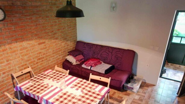 A room with a brick wall, a purple sofa, a checkered table, and a hanging lamp. - Holiday Home Saniv - Holiday Home (Draz)