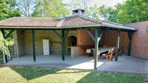 A covered patio area with a brick barbecue and a table with chairs. - Holiday Home Saniv - Holiday Home (Draz)