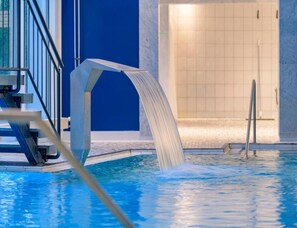 Ein Hallenbad mit Sprungbrett und Wasserspiel.