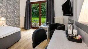 A hotel room with a bed, a desk with a chair, a television, and a view of the outdoors.