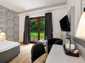 A hotel room with a bed, a desk with a chair, a television, and a view of the outdoors.
