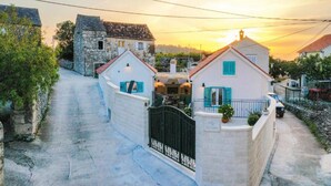 Zona residencial con casas de piedra, un sendero pavimentado y una verja.