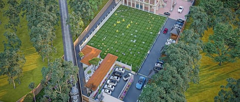 A large hotel with a central courtyard, multiple parking spaces, and surrounding greenery.