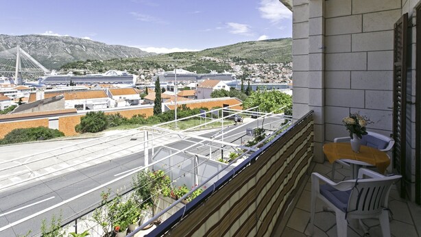 Een balkon met uitzicht op een stadsgezicht, inclusief een brug en cruiseschepen.