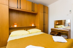A hotel room with a bed, bedside table, mirror, and wooden wardrobe. - Guest House Bridge View - Double Room With Balcony and Sea View (Dubrovnik)