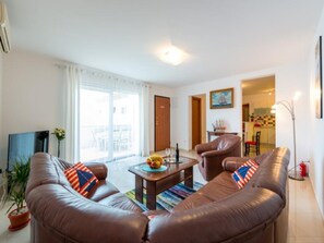 Ein Wohnzimmer mit braunem Ledersofa, einem Couchtisch und einer Topfpflanze.