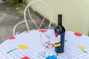 Eine Weinflasche, ein Glas und ein Tisch mit Rautenmuster und floralen Verzierungen.