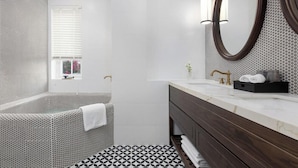 A modern bathroom with a freestanding bathtub, a large mirror, and a vanity with a marble countertop. - Bach Dang Hotel (Hai Phong)