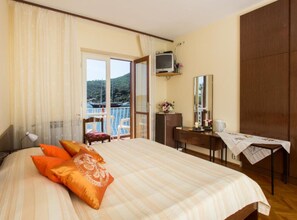 A hotel room with a bed, a desk, a chair, a television, and a balcony with a view of the sea. - Villa Malfi - Standard Double Room With Sea View (Dubrovnik)