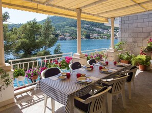 A terrace with tables and chairs, overlooking a body of water and a hillside town. - Villa Malfi - Standard Double Room With Sea View (Dubrovnik)