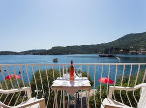 A table with a bottle and glasses, overlooking a lake with boats and hills. - Villa Malfi - Standard Double Room With Sea View (Dubrovnik)