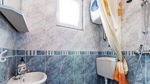 Um banheiro com pia branca, vaso sanitário e chuveiro com cortina.