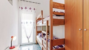 Um quarto com uma cama de solteiro, uma mesa de cabeceira com abajur e um guarda-roupa.