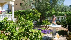 A garden with a fountain, trees, and a white building with balconies. - Mobile Homes Bella Vita 1 (Biograd na Moru)