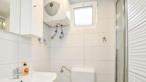 A bathroom with a white sink, toilet, and shower. There is a window above the toilet and a mirror above the sink. - Mobile Homes Bella Vita 1 (Biograd na Moru)