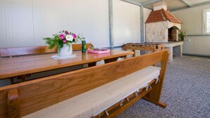 A room with a wooden table, benches, a flower vase, and a stone fireplace. - Mobile Homes Bella Vita 1 (Biograd na Moru)