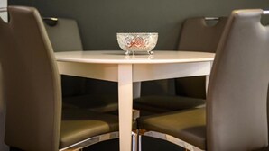Una mesa redonda con un cuenco decorativo en el centro, rodeada por cuatro sillas con asientos acolchados.