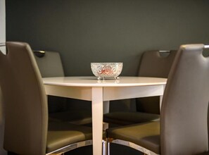 Ein runder Tisch mit einer dekorativen Schale in der Mitte, umgeben von vier Stühlen mit gepolsterten Sitzflächen.