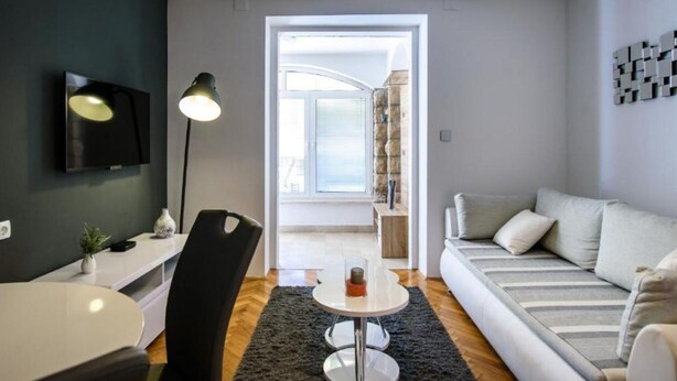 Una sala de estar moderna con una televisión de pantalla plana, un sofá, una mesa de comedor y una lámpara.