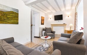 Ein Wohnzimmer mit Kamin, Flachbildfernseher und einem Bild an der Wand.