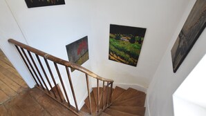 Eine Holztreppe mit Handlauf, weißen Wänden und drei gerahmten Bildern.